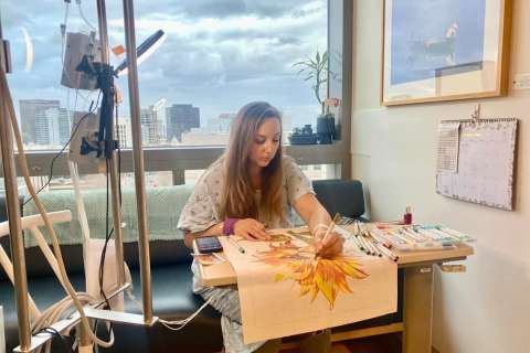 A patient creates artwork in her hospital room.