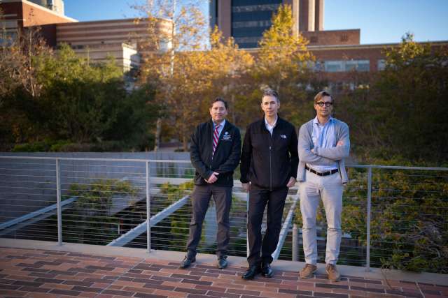 Drs. Noah Federman, Robert Damoiseaux and David Ulmert standing on a walkway surrounded by greenery and buildings.