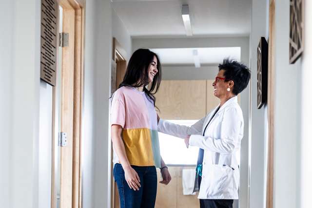 a female young adult speaking with a female doctor inside of a clinic