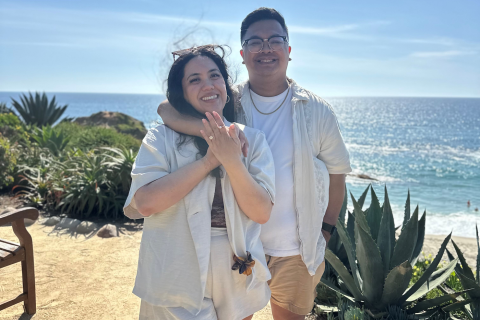 Man with arm around fiancé and smiling, having just proposed.